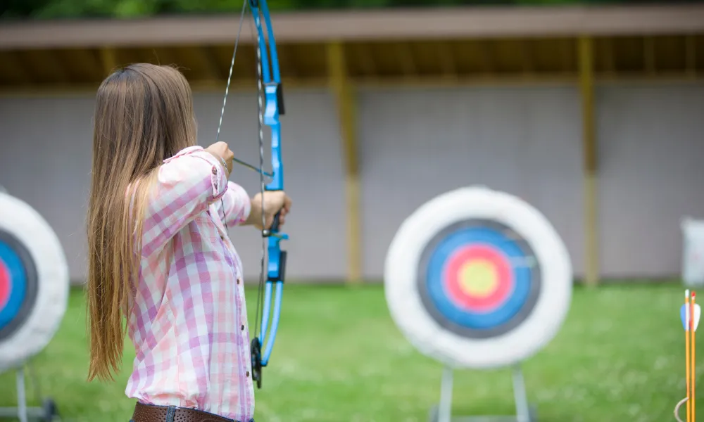 Woman doing target practice with bow and arrow.