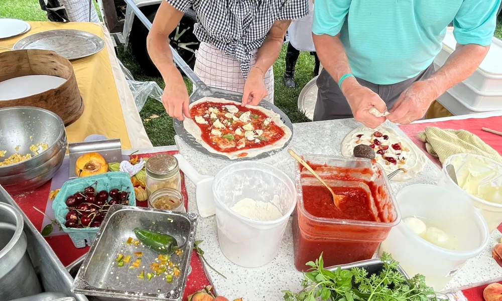 Two people making homeade pizzas.