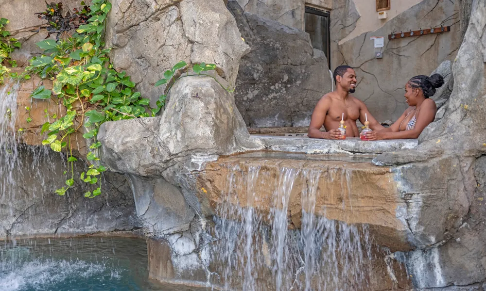 Couple enjoying drinks in the jacuzzi at Grand Cascades Lodge Biosphere Pool