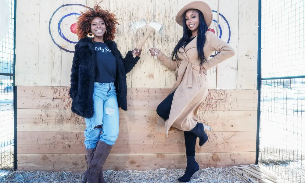 Two women holding axes in front of targets.