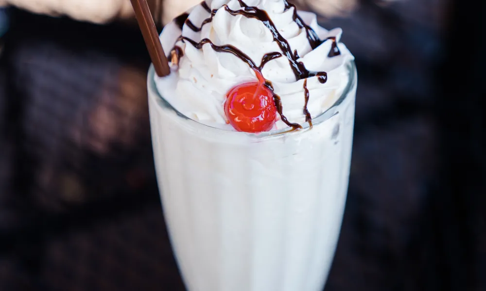 Vanilla milkshake with whipped cream and a cherry on top