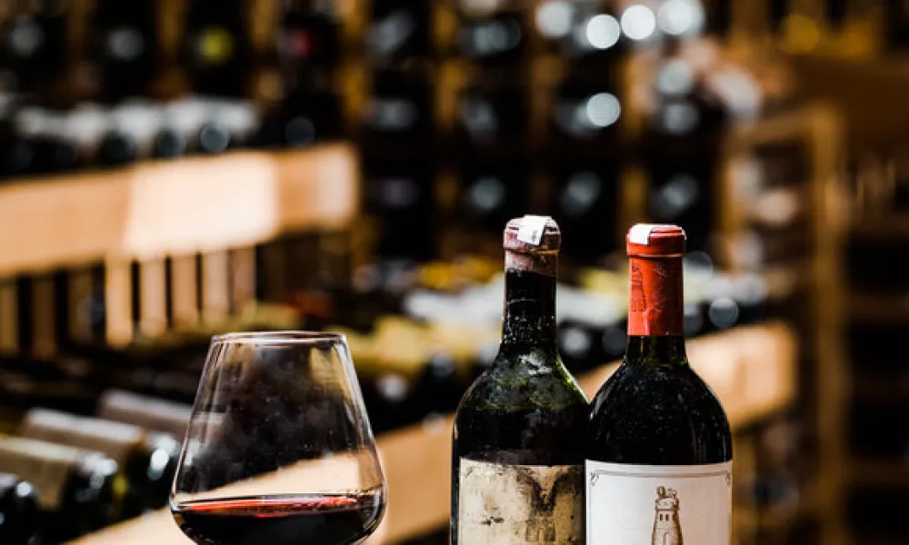 Two bottles of wine and glass of wine set up wooden box.