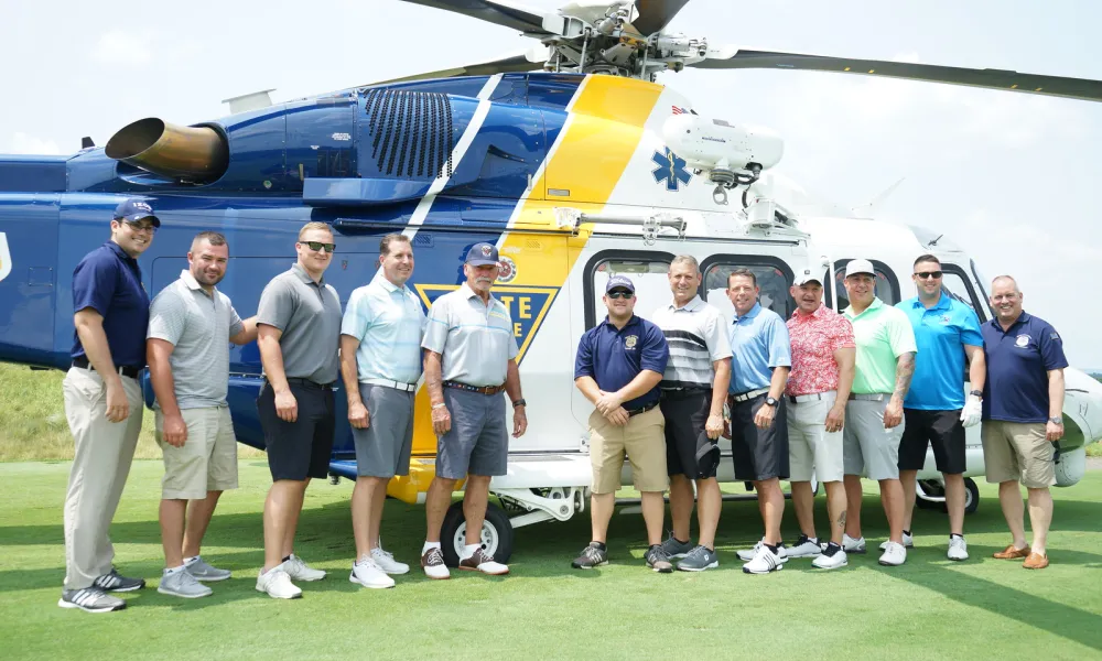 Golfers posing in front of NJ State Police helicopter.