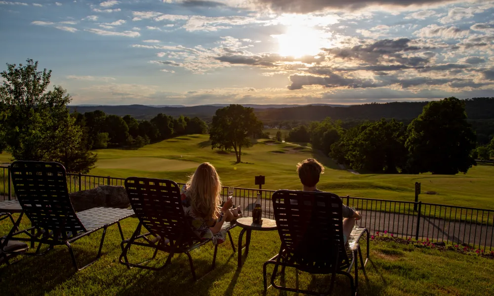 Woman and man sitting in lounge chairs looking at a sunset.