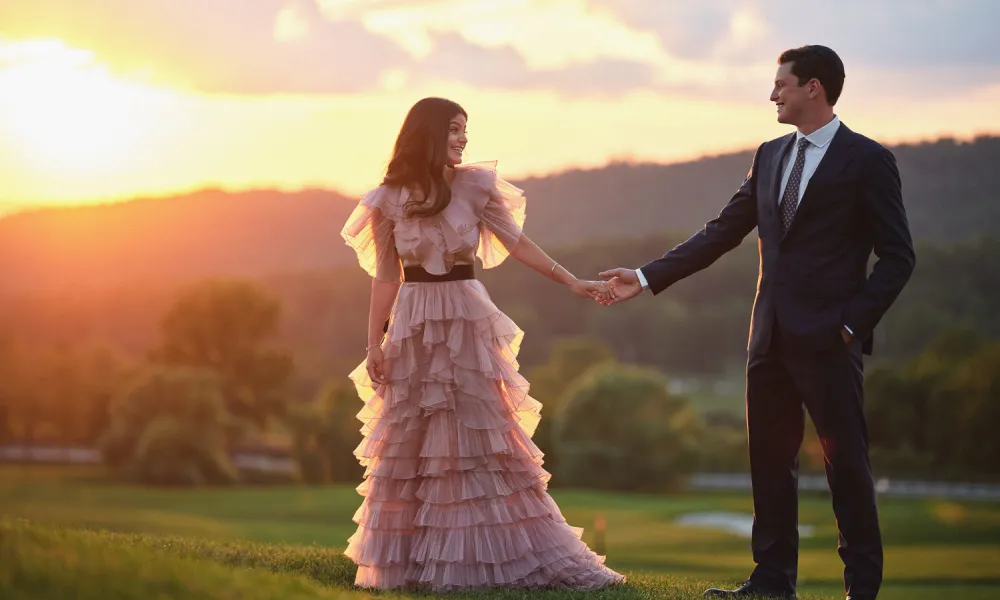 Bride wearing a pink wedding dress with groom on a golf course at sunset