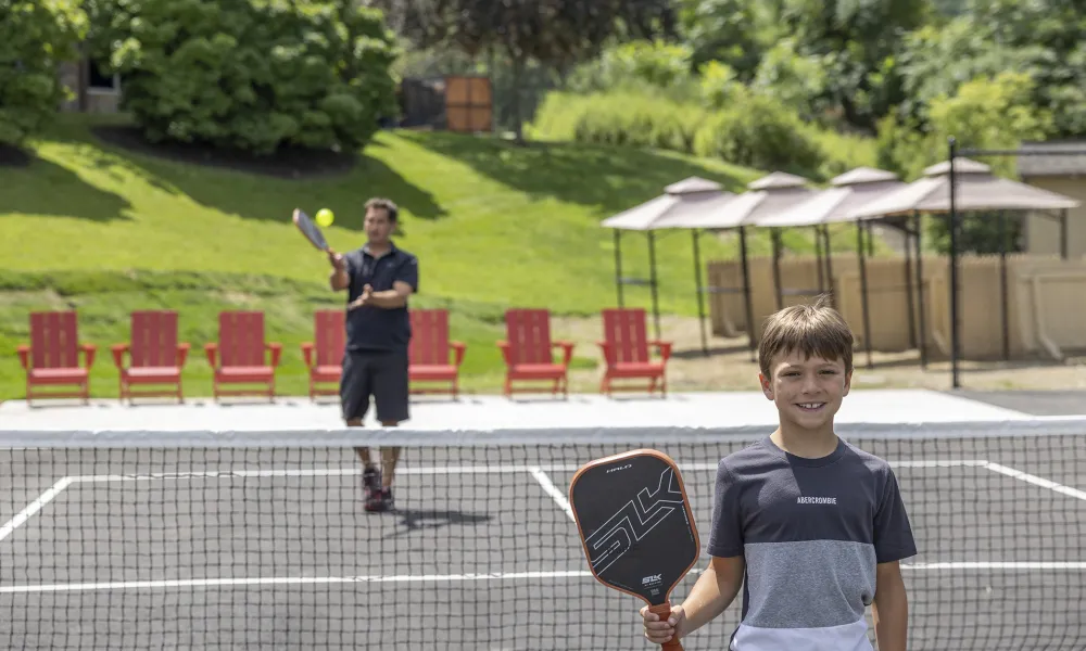 Boy and father playing pickleball.