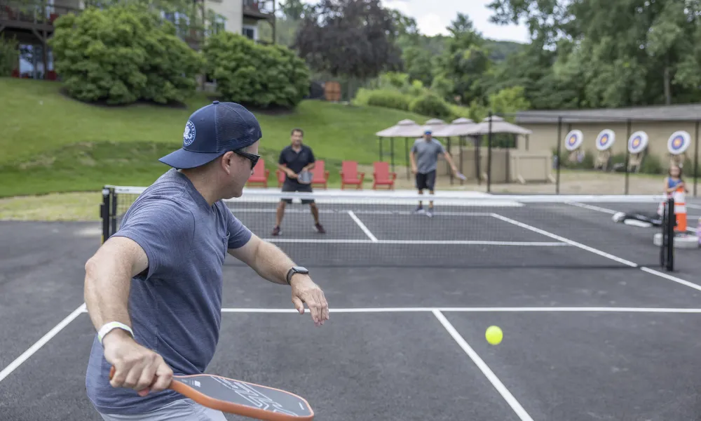 Man getting ready to hit ball over pickleball net.