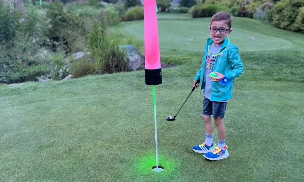 Child playing glow in the dark mini golf.