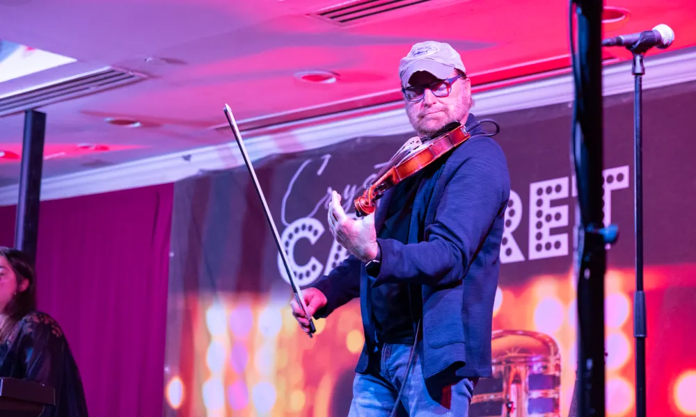 Man playing violin on Crystal Cabaret stage.