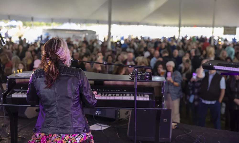 Woman playing the keyboard with music fest crowd in front of her.