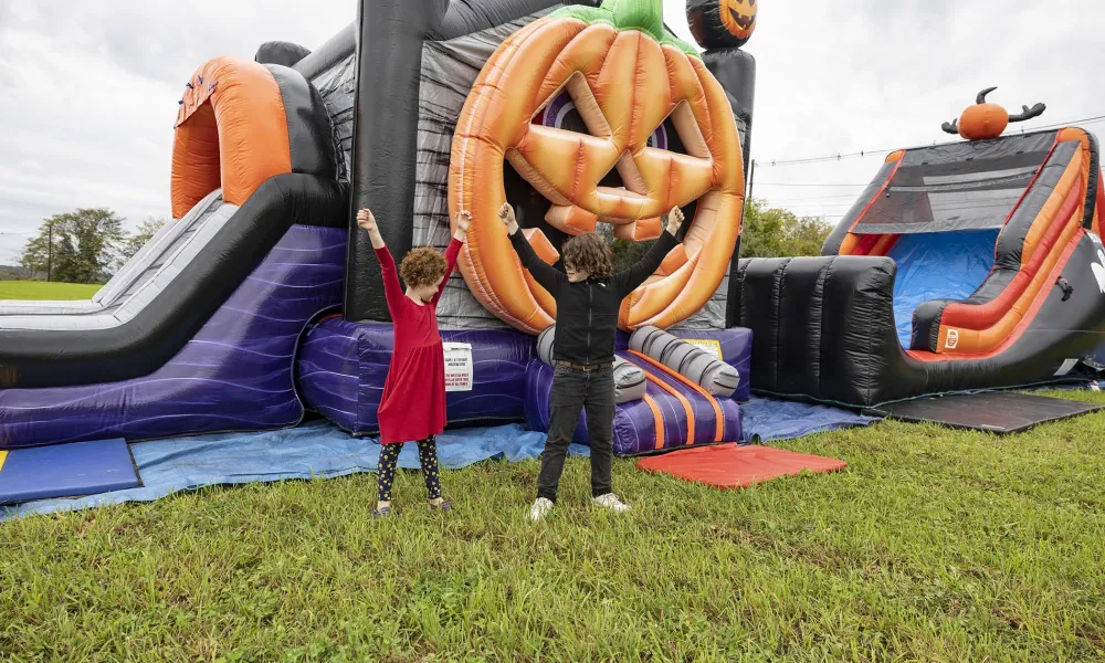 Two children standing in front of halloween themed blow up obstacle course.