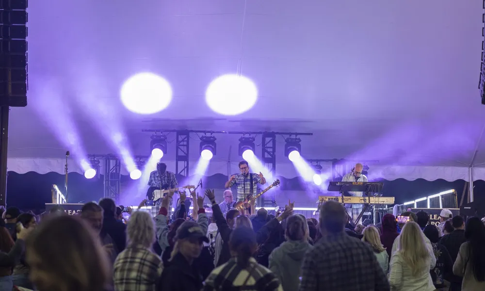 The Nerds on stage at music fest with bright lights illuminating the stage.