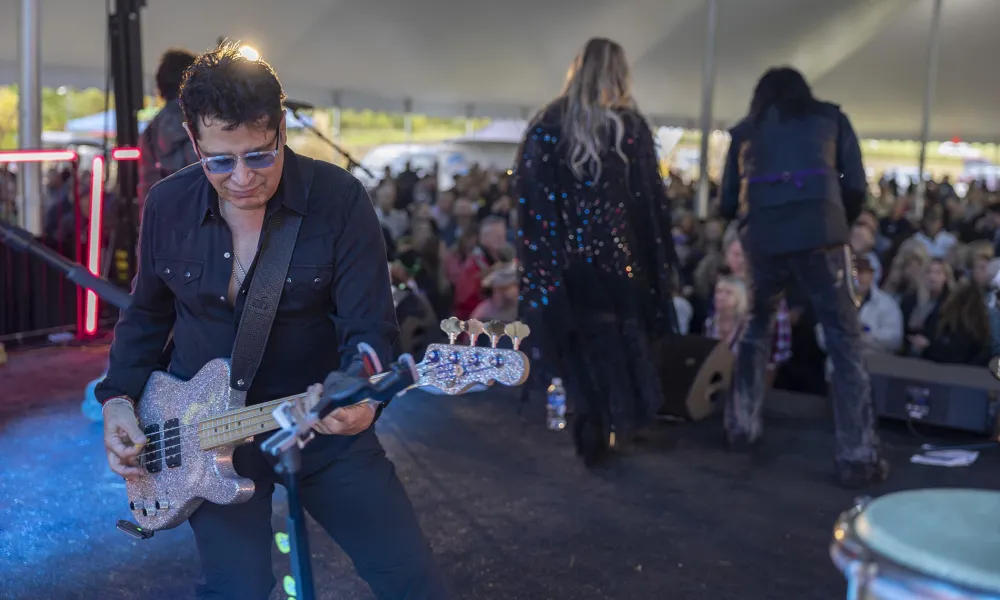 Man playing guitar on stage at music fest.