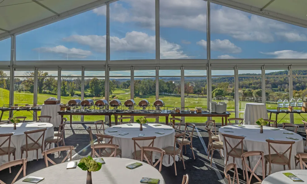 Tables and chairs set up in Big Sky Pavillion with view of mountains in the windows. 