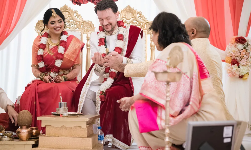 Bride and groom sitting in chairs during their Indian wedding ceremony.