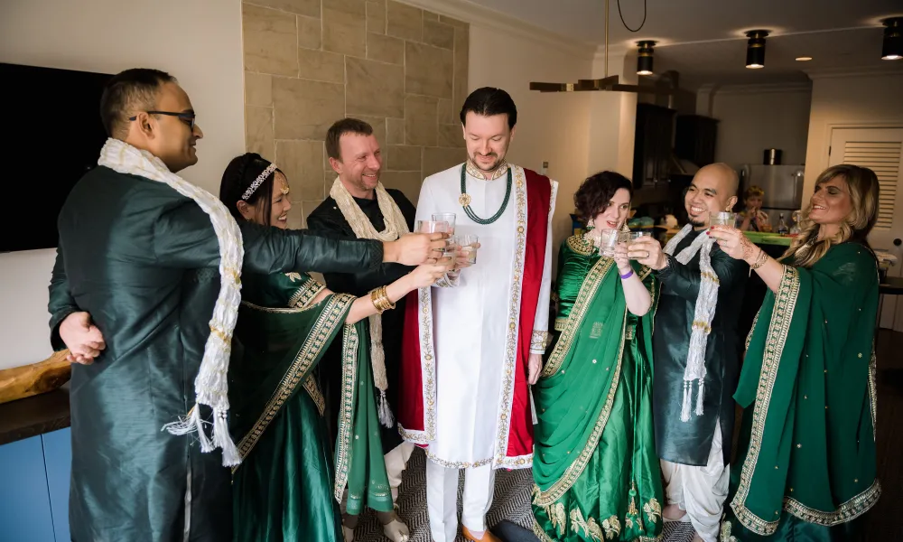 Indian groom cheersing drinks with friends and family.