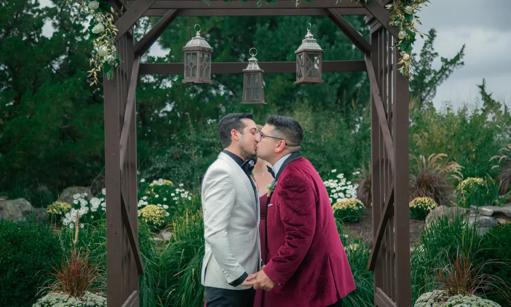 Grooms kissing during their wedding ceremony.