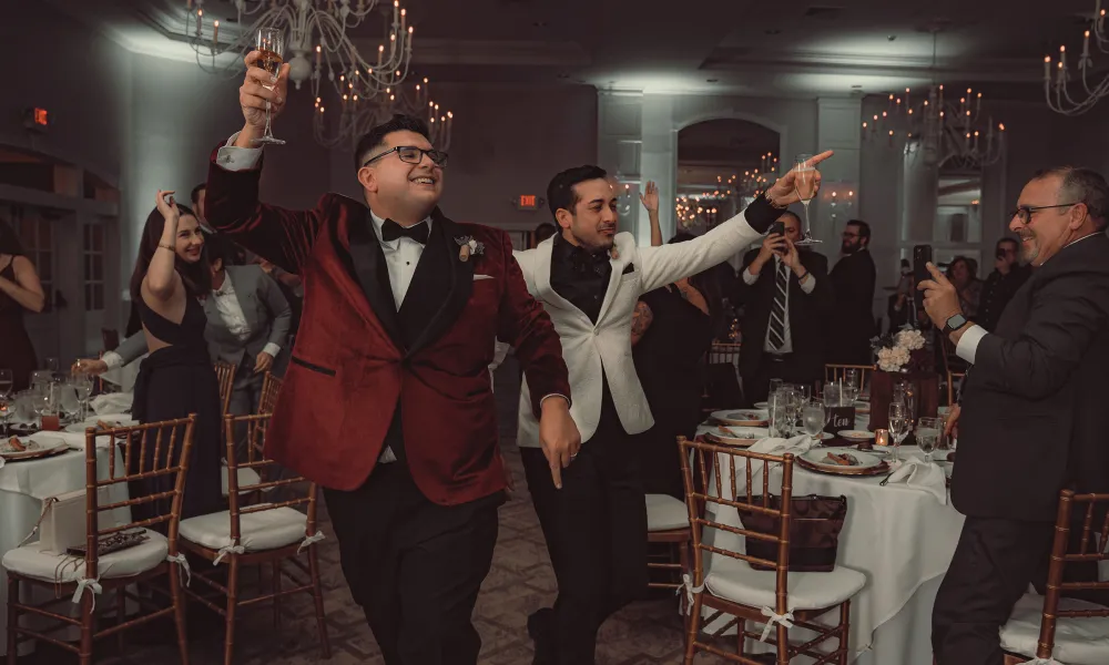 Grooms, holding glasses, making their wedding reception entrance.