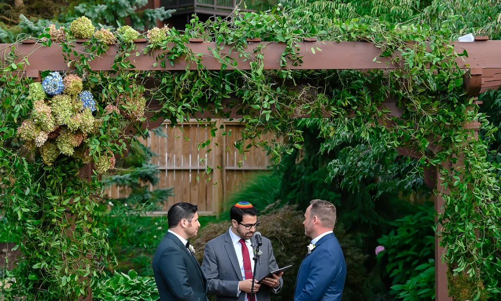 Wedding ceremony for two grooms standing with their officiant.