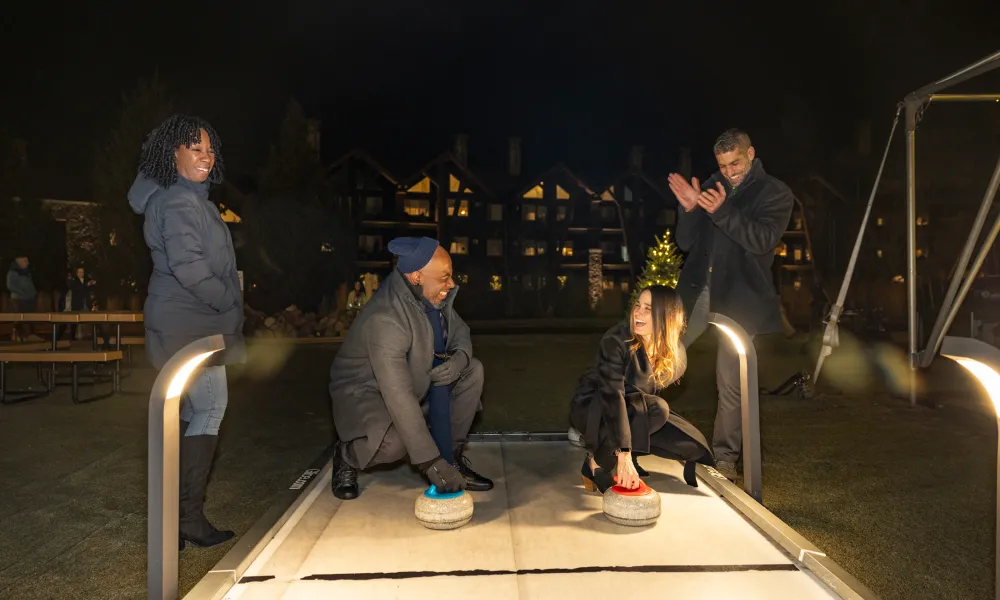 Group of four friends curling outside Grand Cascades Lodge.