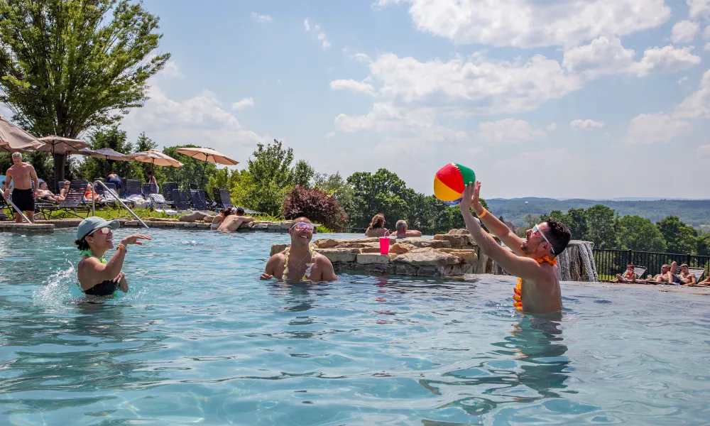 Woman and two men playing with a blow up ball in the Vista 180 pool.