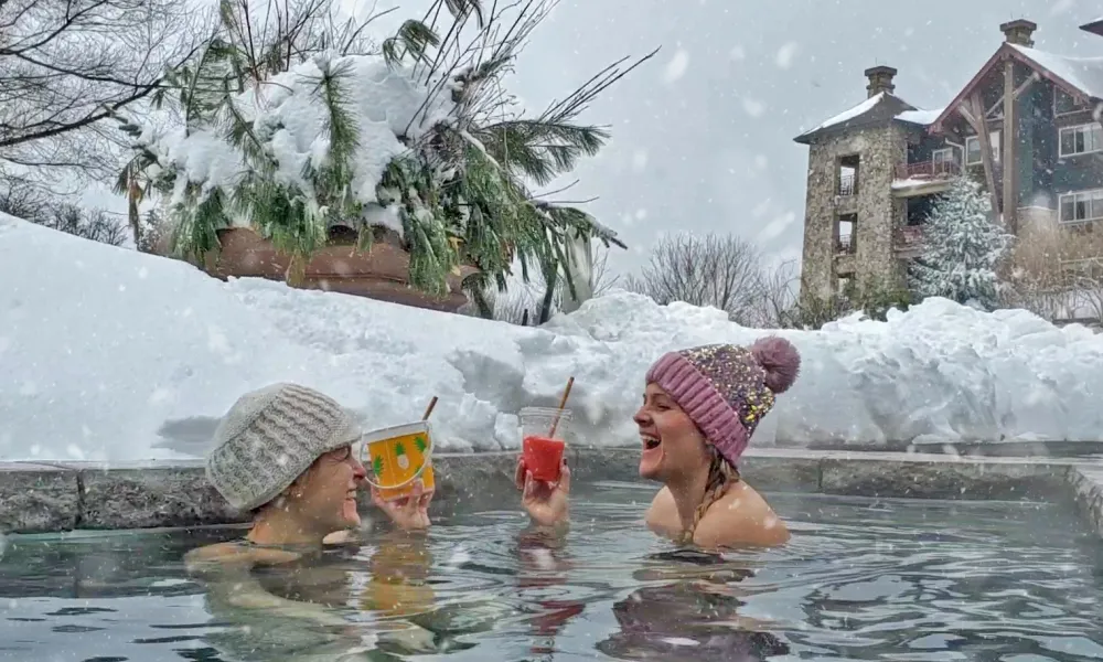 Two women having drinks in the outdoor snow pool at Grand Cascades Lodge.