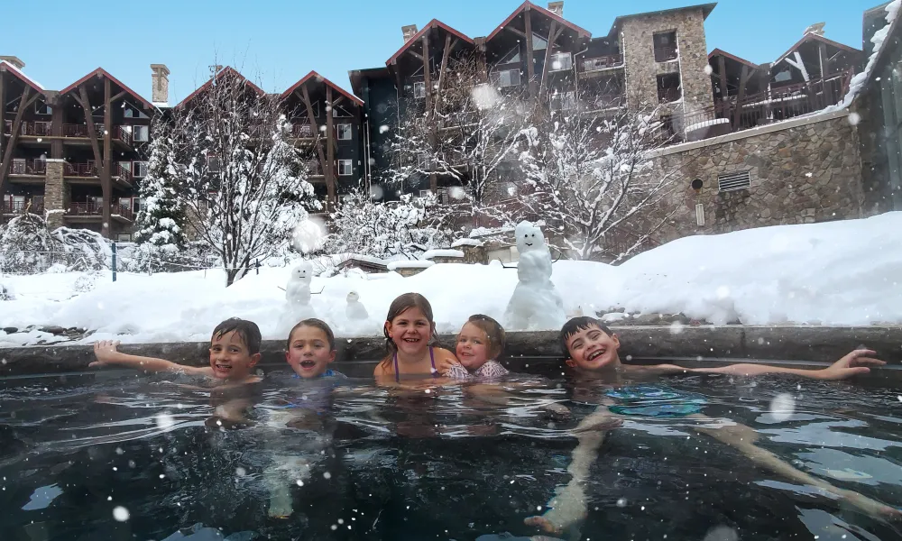 Group of 5 children in outdoor snow pool at Grand Cascades Lodge.