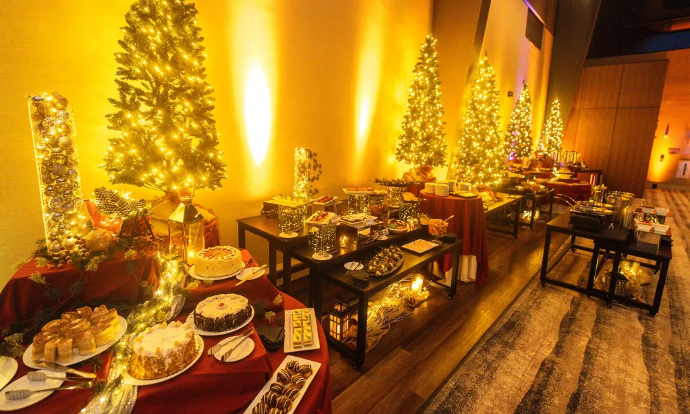 Dessert tables et up in front of Christmas trees during party.