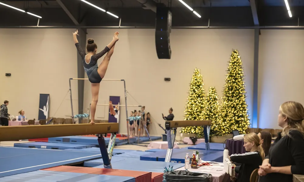 Young girl performing on beam during gymnastics competition in Canyon Ballroom.