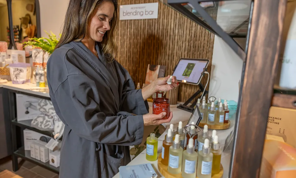 Woman adding oils to her custom lotion at Elements Spa blend bar.