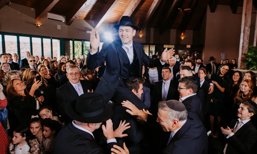 Men holding groom up on their shoulders during wedding ceremony.