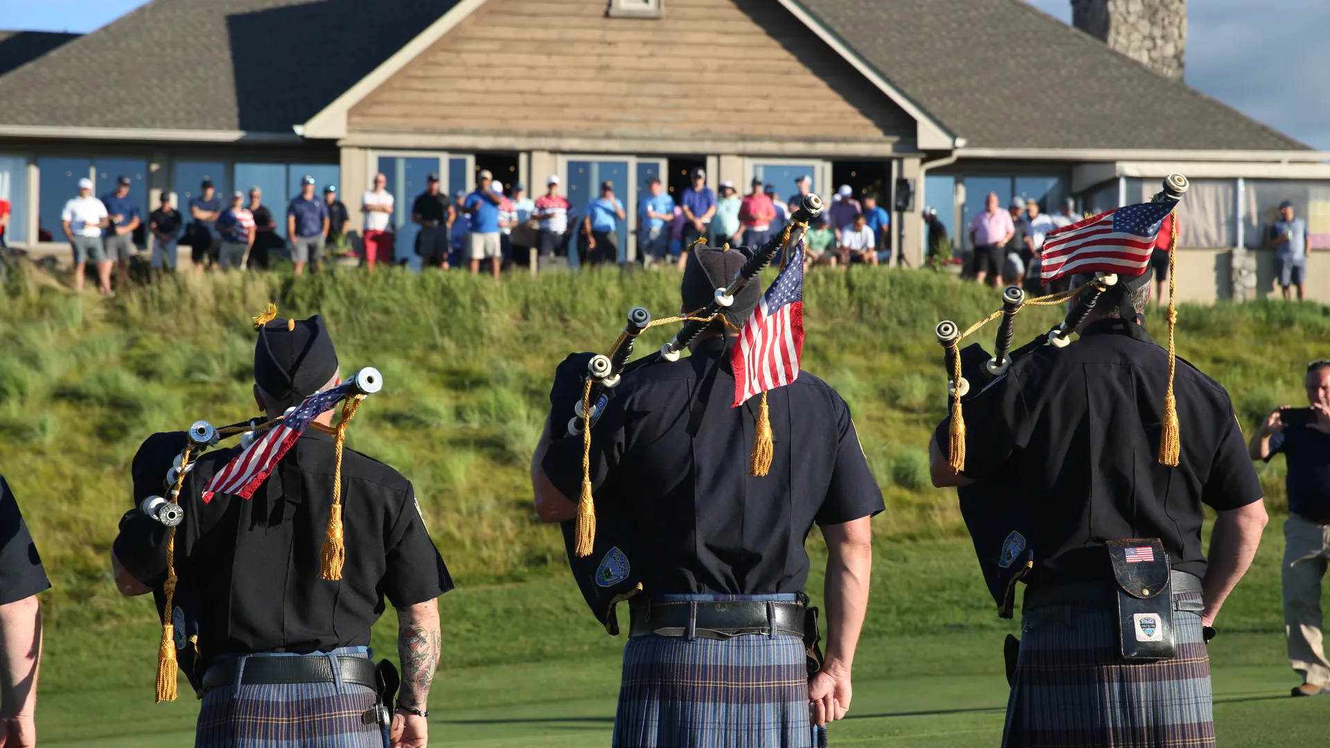 Bagpipers stand with American flags facing towards Ballyowen Clubhouse