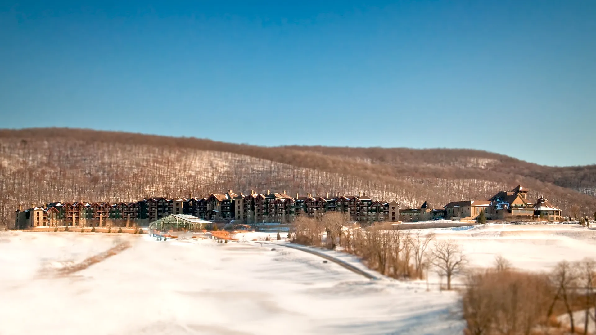 Distant view of Grand Cascades Lodge in front of the snowy mountains