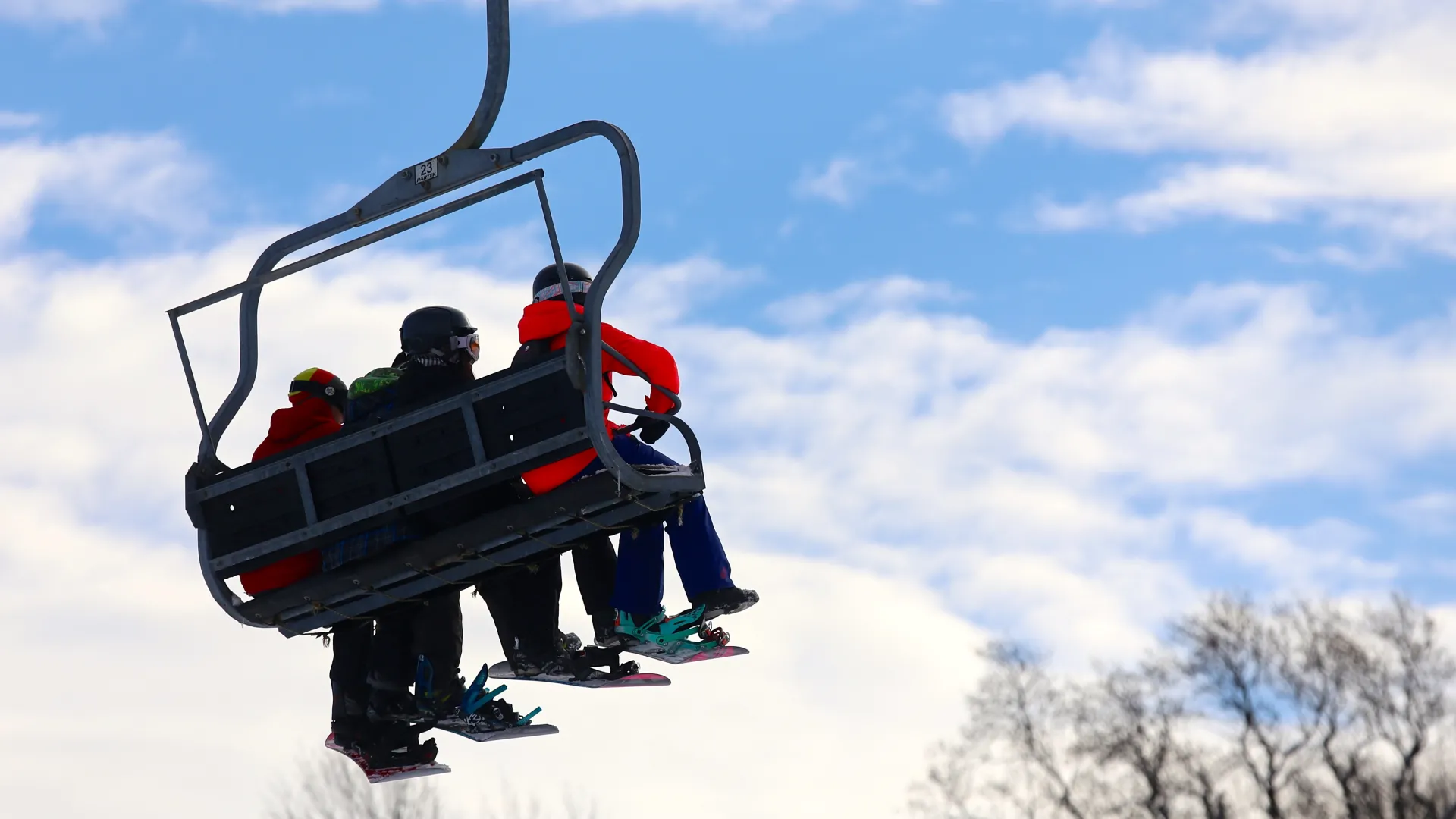 Three people sitting on ski lift.