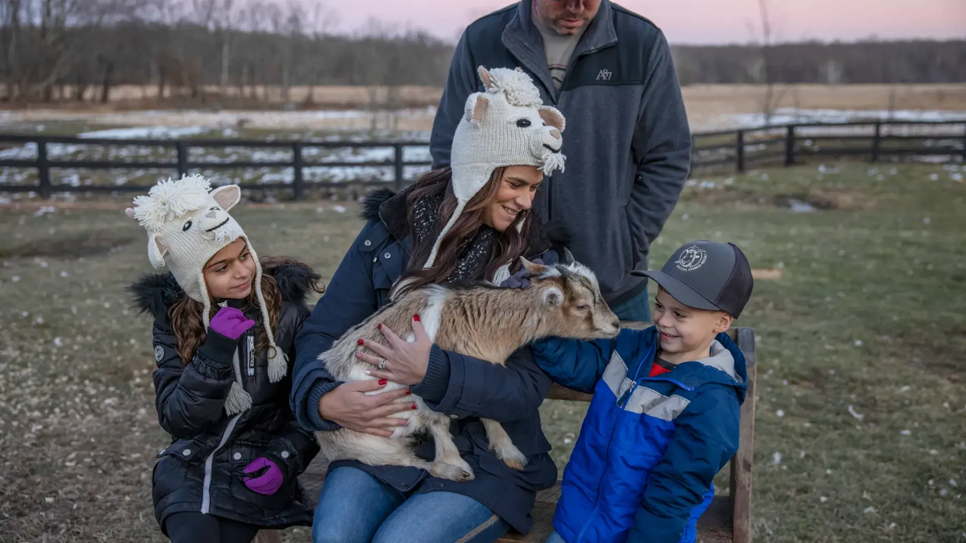 Family of four pose with a baby goat.