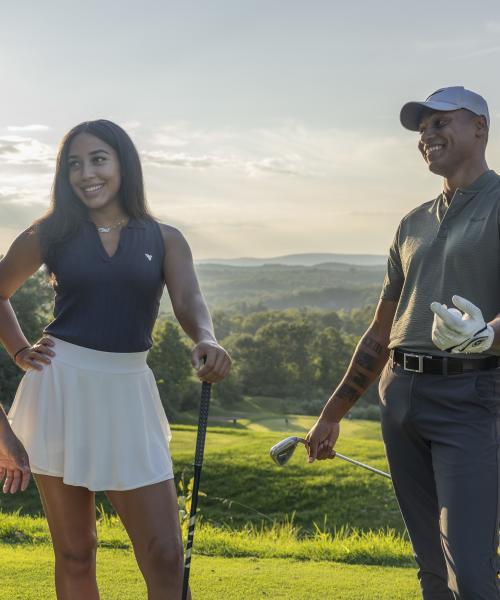 Two women and two men stand together on golf course, 