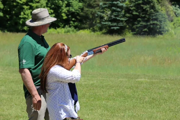 Instructor helping woman shoot laser clays. 