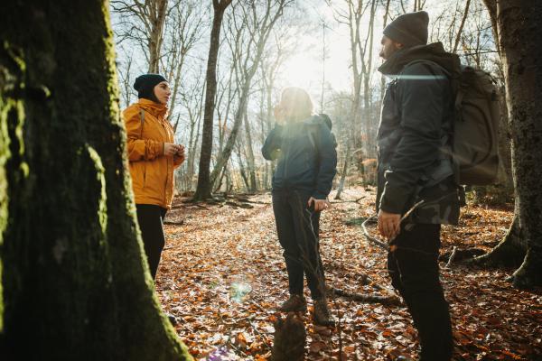 Three people talking out in the woods in winter.