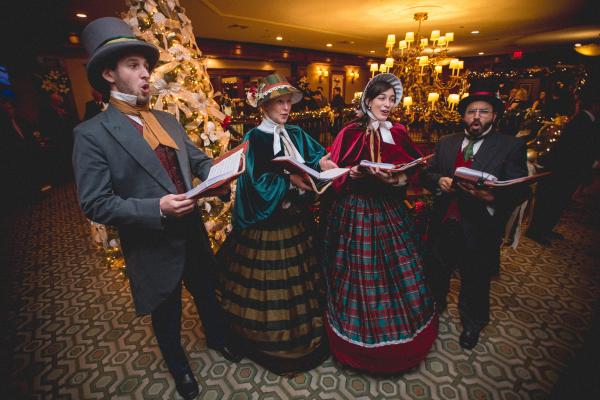 Carolers singing in front of decorated Christmas tree in Crystal Springs Clubhouse