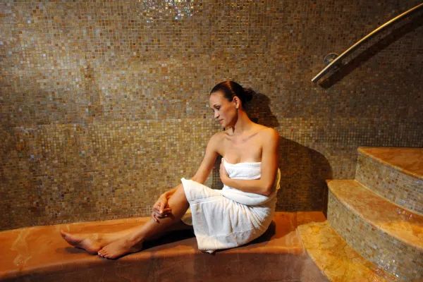 Woman in white towel relaxing in Elements Spa sauna. 