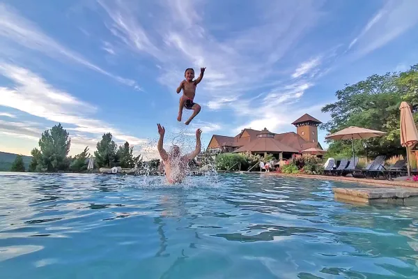 Father throwing son in air while they swim in vista 180 pool.