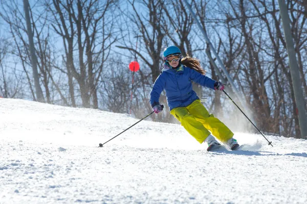 Person in blue jacket skiing down mountain.