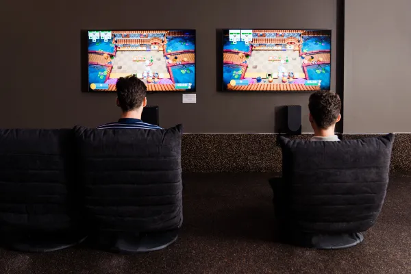 Two children sitting in front of two tvs playing video games.