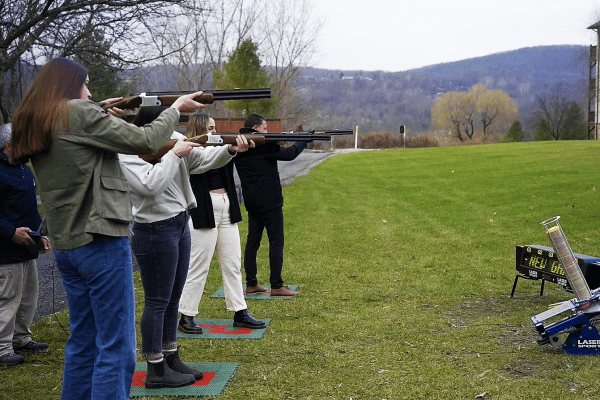 Group of people pointing laser clay guns at target.