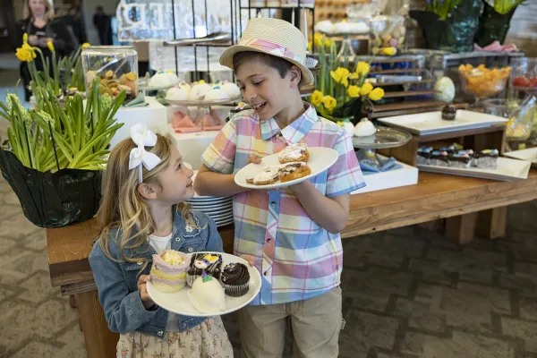 Two children looking at each other holding plates of desserts.