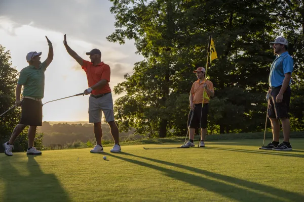 Men high fiving on putting green