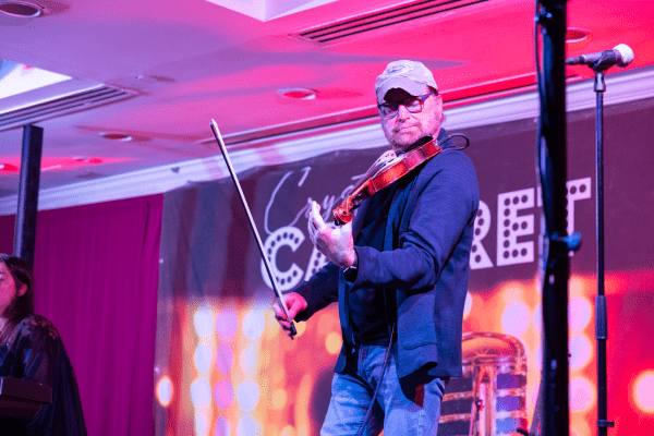 Man playing violin on Crystal Cabaret stage.