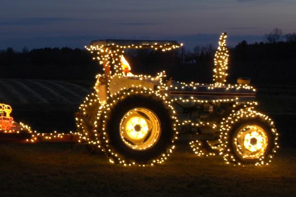 Tractor that is covered in Christmas lights.