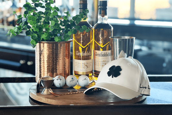 White hat with four leaf clover, three golf balls, Glenfidditch scotch.