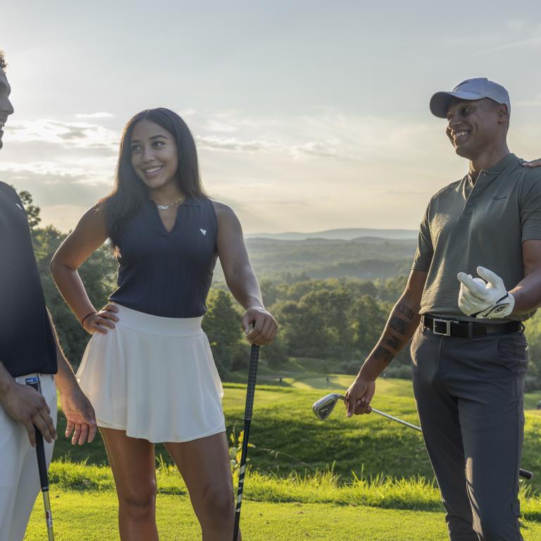 Two women and two men stand together on golf course, 